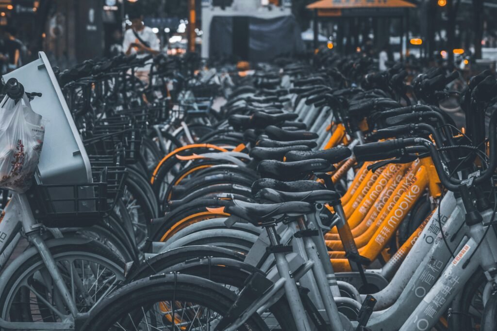 A row of gray and orange rental bicycles parked in an urban setting, ready for transportation use.